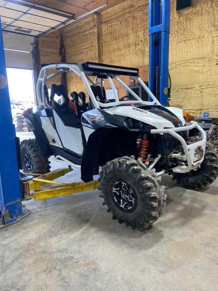 Can-Am Maverick X3 1000R side-by-side with lift kit and mud tires inside Say When Motorsports shop
