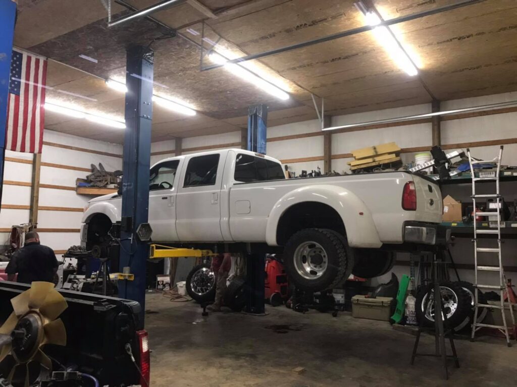 White Ford Super Duty Dually lifted in shop for diesel engine service and repair at Say-When Motorsports in Austin, Arkansas