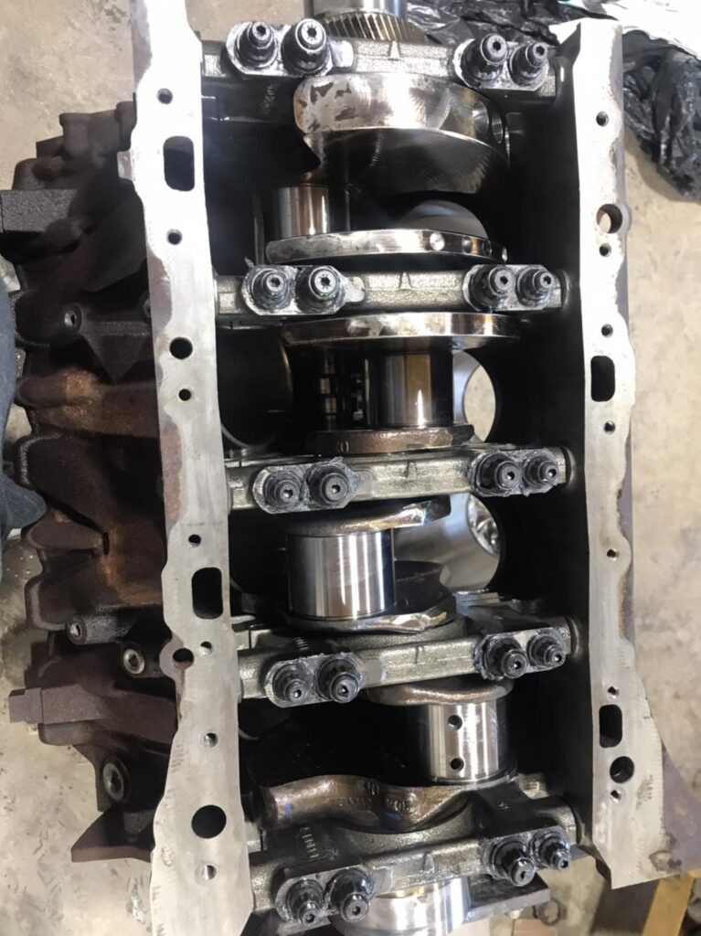 Diesel engine crankshaft and connecting rods inside engine block during rebuild at Say When Motorsports
